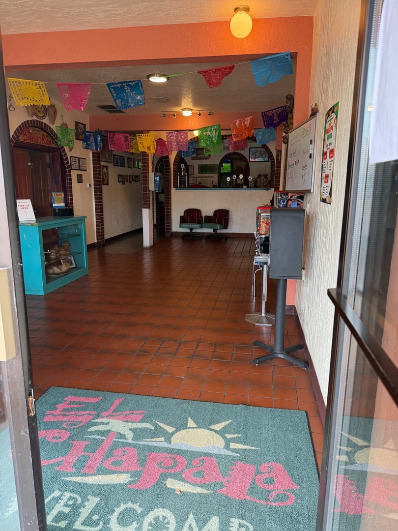 Entrance to a Mexican restaurant with colorful papel picado banners and a welcome mat.
